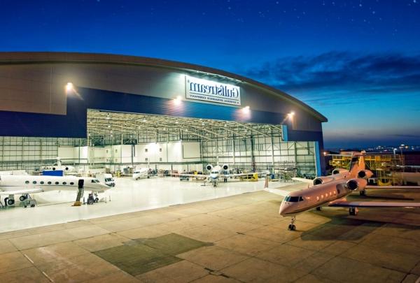 湾流服务中心外的夜晚. Planes inside hangar and outside on apron.